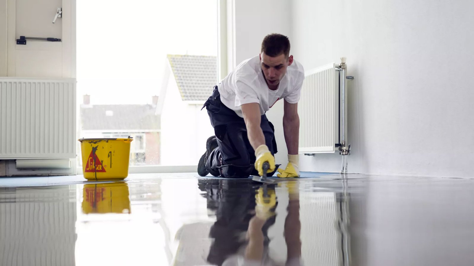 Self-leveling underlayment being poured across a concrete slab