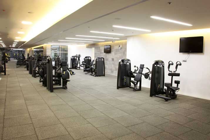 Modern corporate fitness room with rubber tile flooring and a run of strength machines