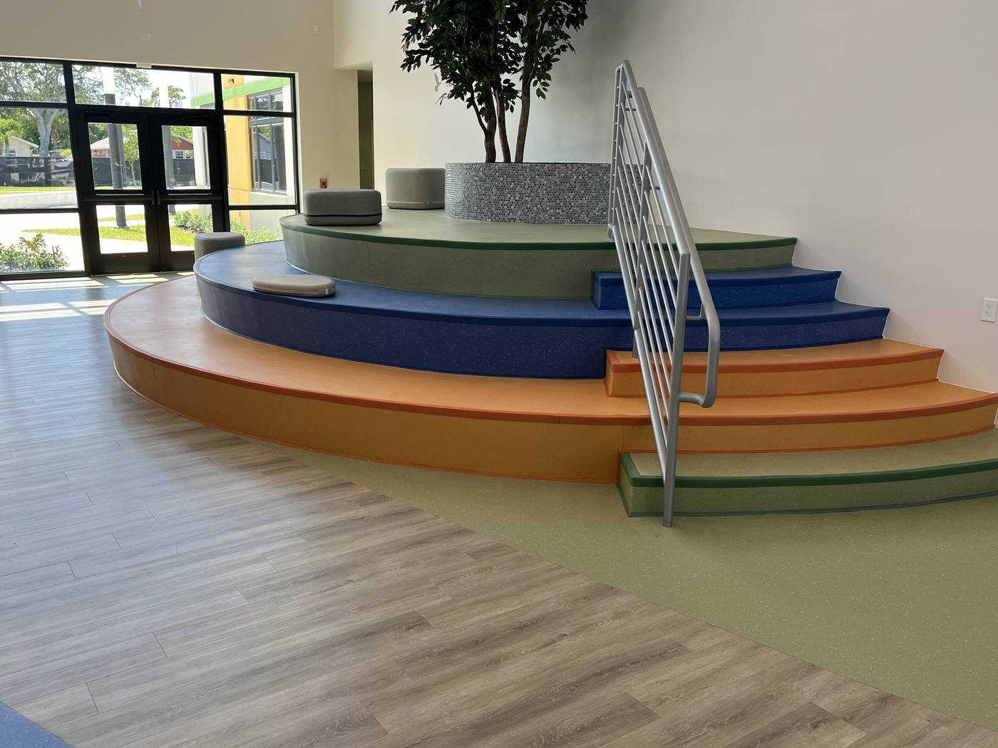 Tiered seating in the Greenacres Youth Program lobby finished in ABPure rubber in olive green, orange and electric blue