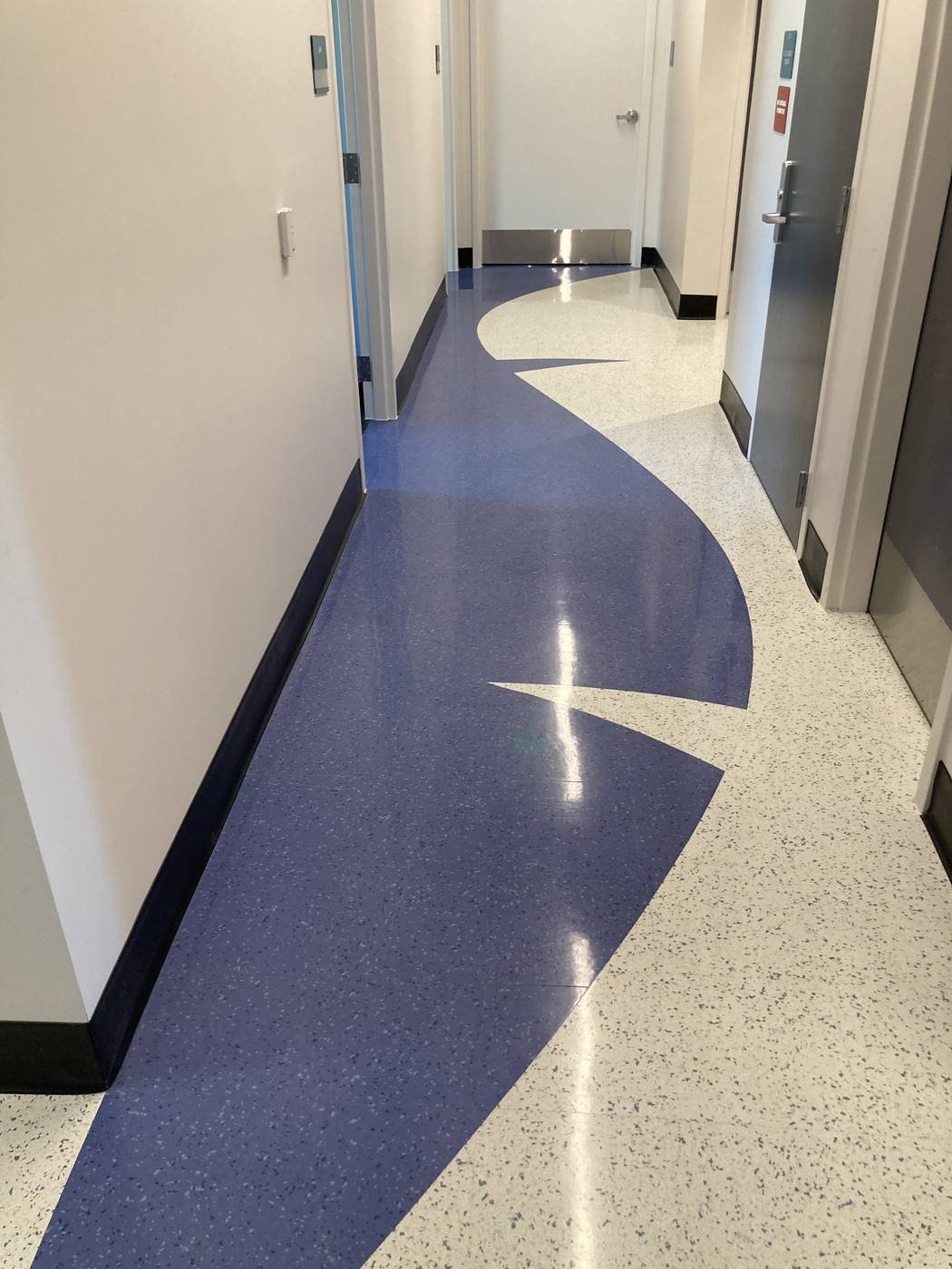 Clinical corridor with a custom curved blue Texas Granite inlay in a white speckled field