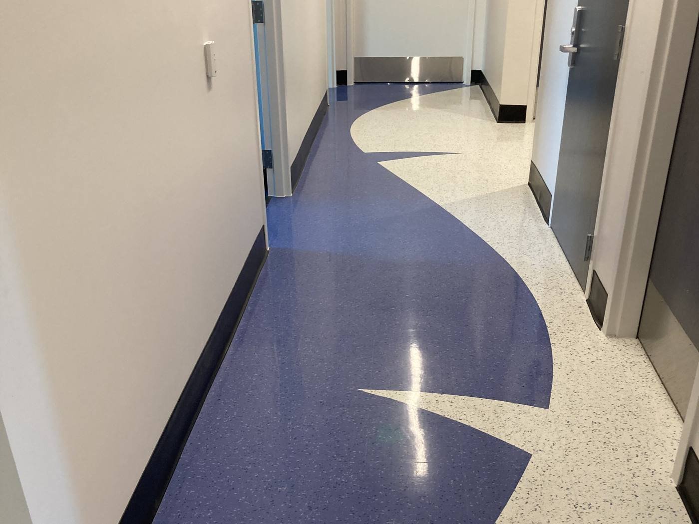 Clinical corridor with a custom curved blue Texas Granite inlay in a white speckled field